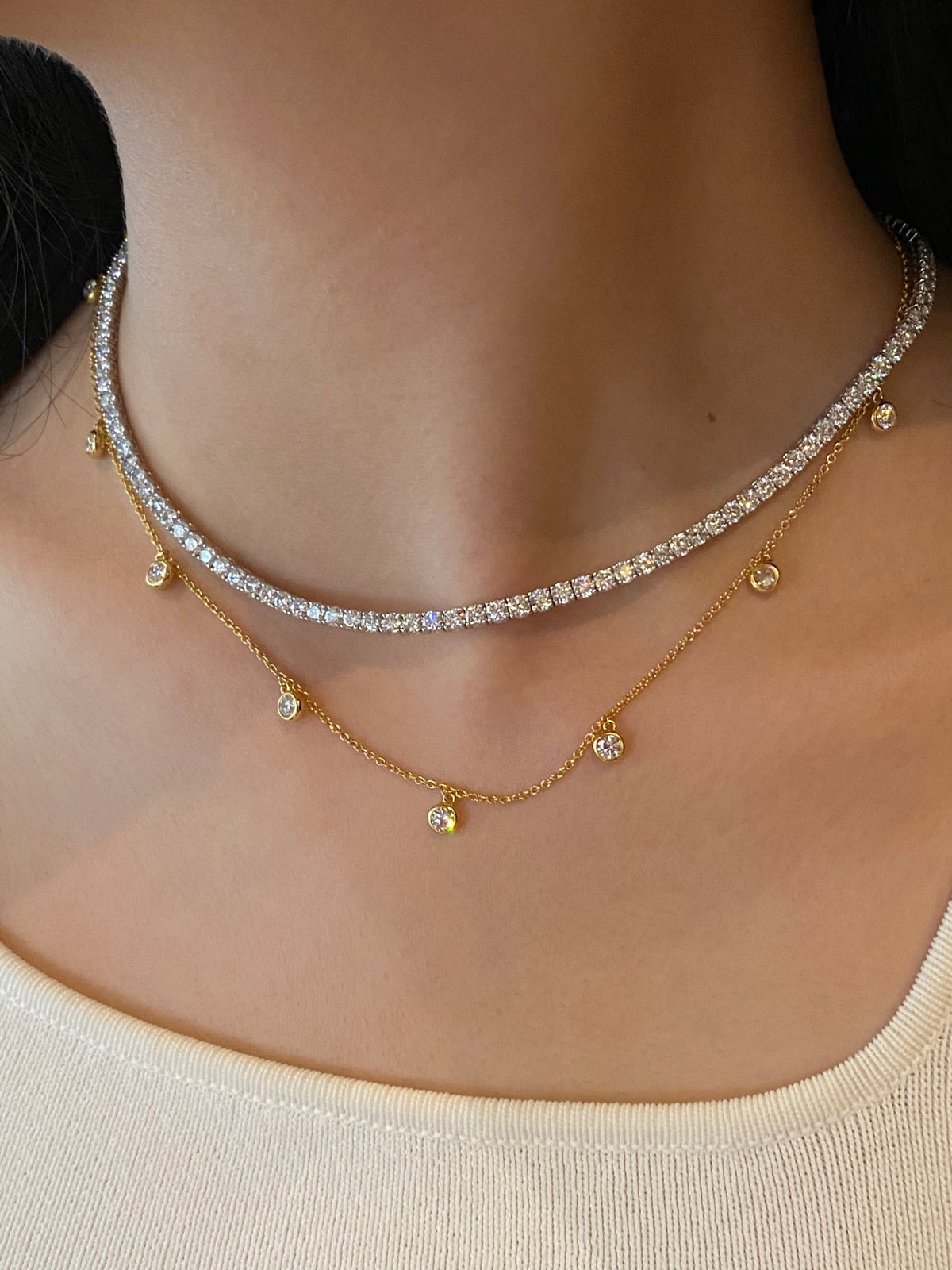 Layered styling of the 18K yellow gold ten-stone diamond necklace below a separate tennis necklace