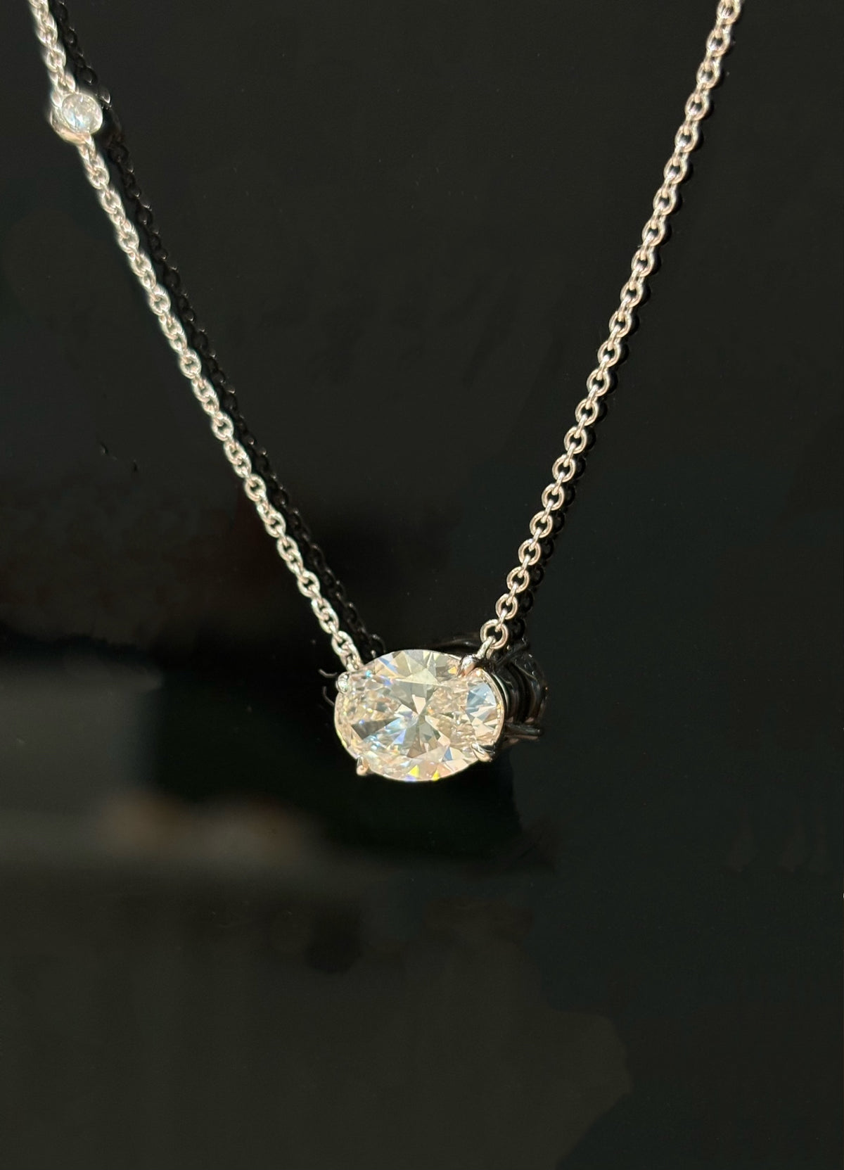 East-west oval lab-grown diamond necklace with one round diamond accent, original detail view 1