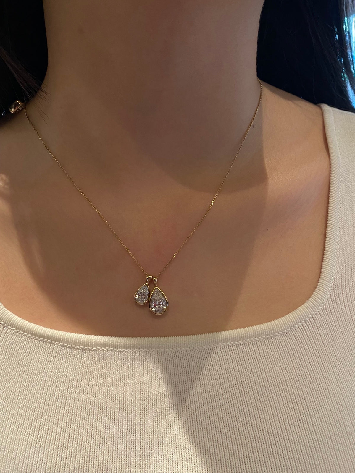 Two sizes of yellow-metal pear diamond pendants styled together for comparison, one necklace sold per unit
