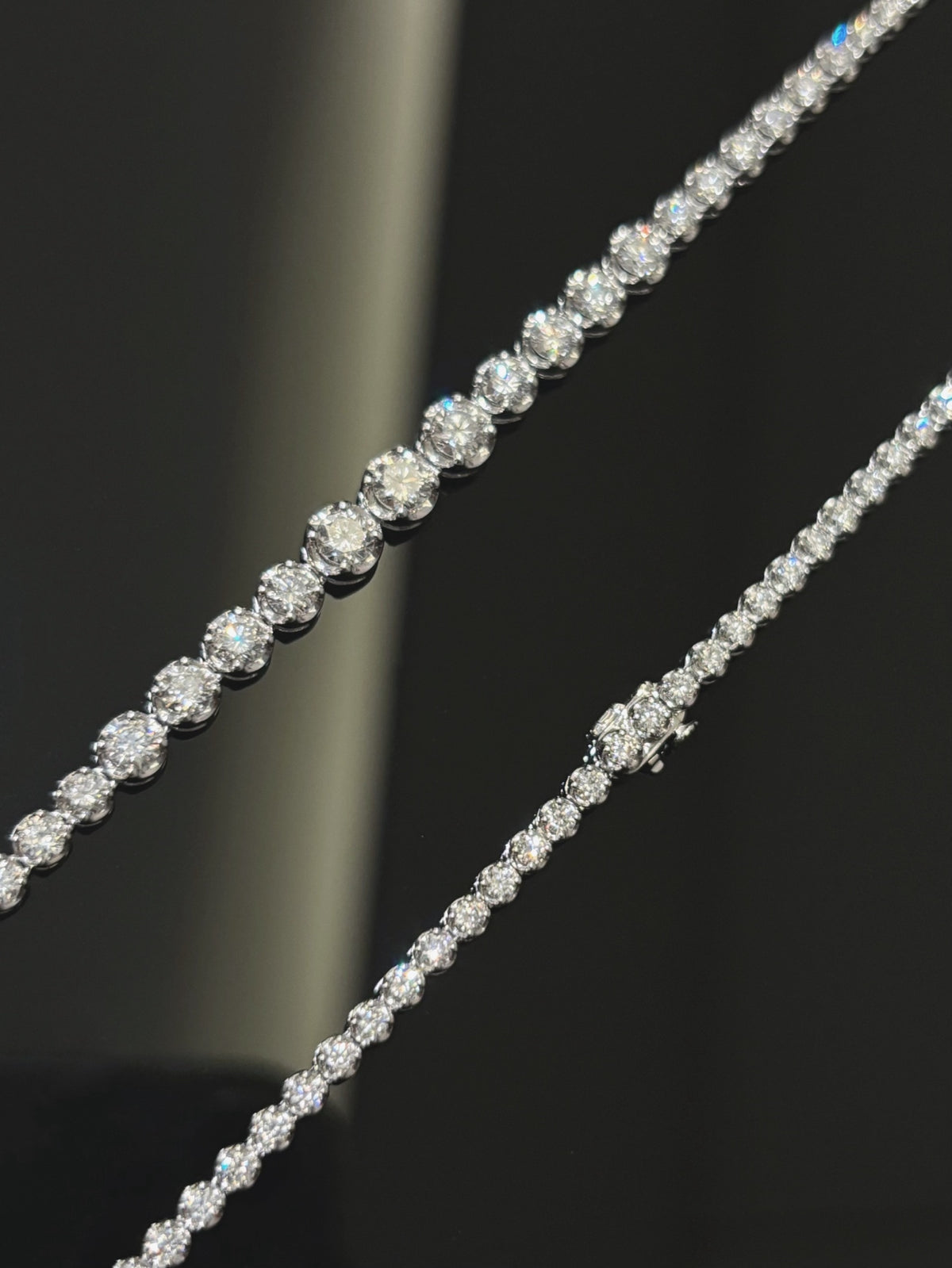Graduated round diamond tennis necklace in white metal, smaller rear stones and box clasp detail
