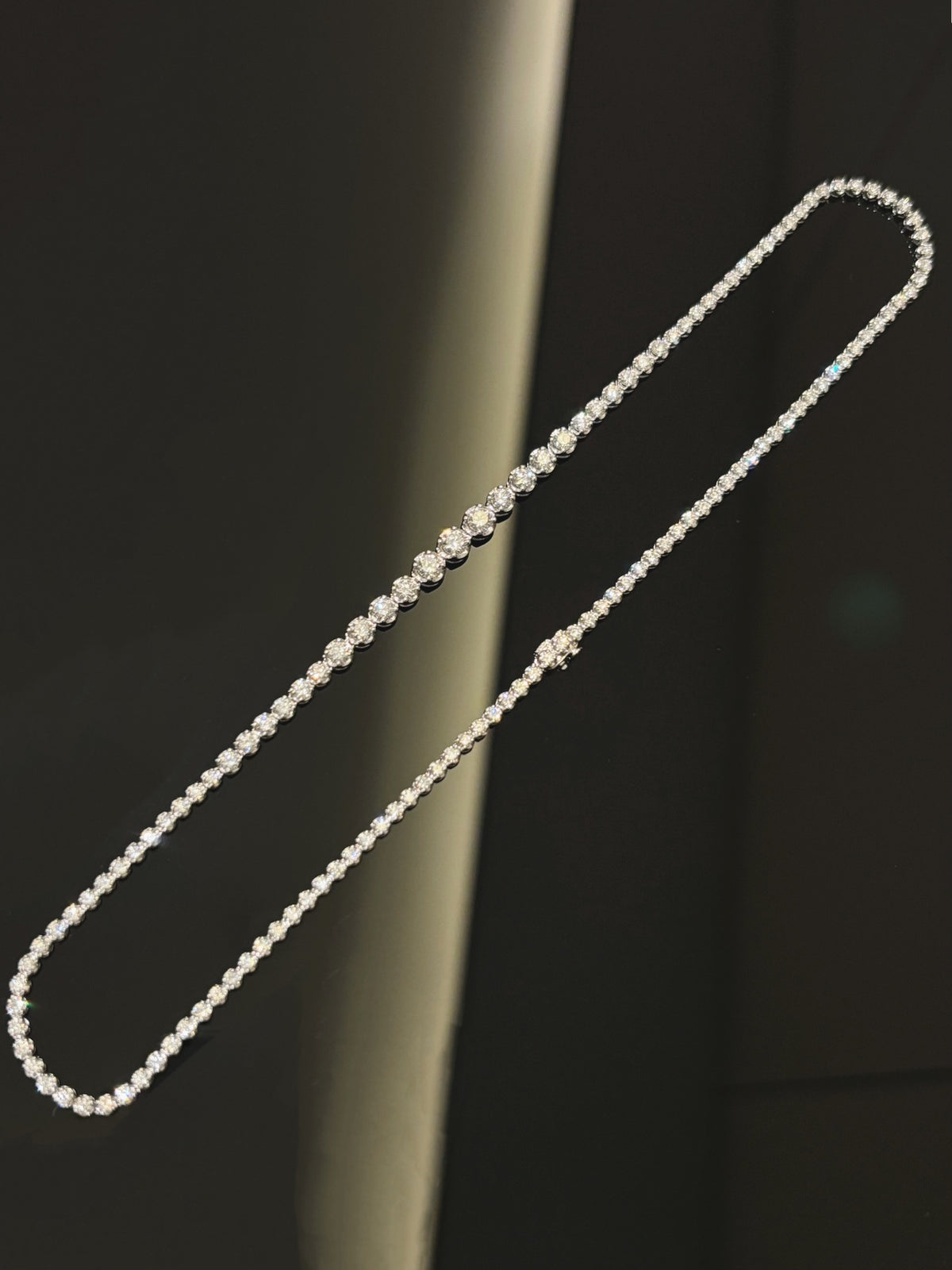 Graduated round diamond tennis necklace in white metal, folded full necklace view
