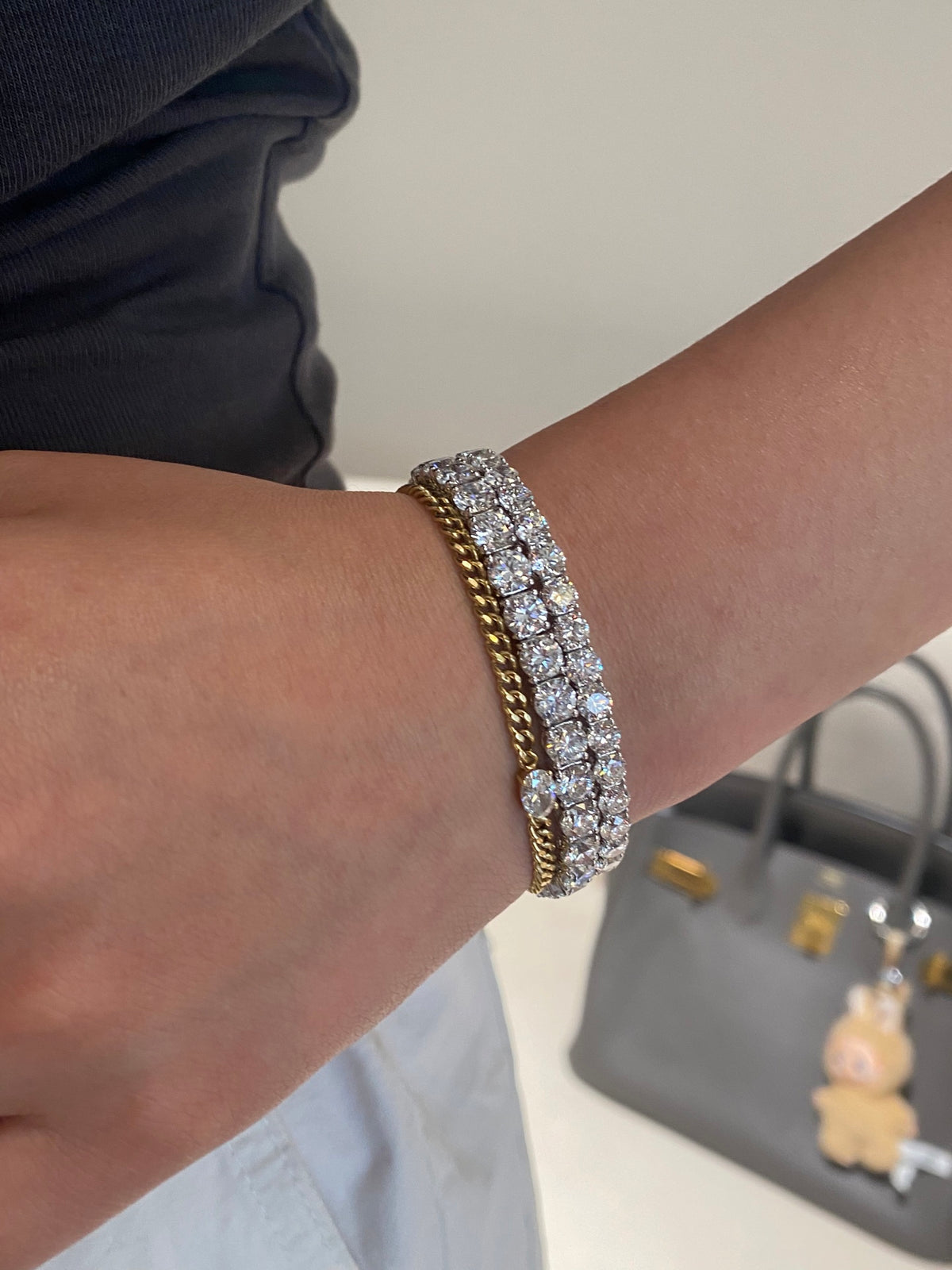 Larger white-metal tennis bracelet shown beside a smaller tennis bracelet and a gold chain bracelet; one larger bracelet sold per unit