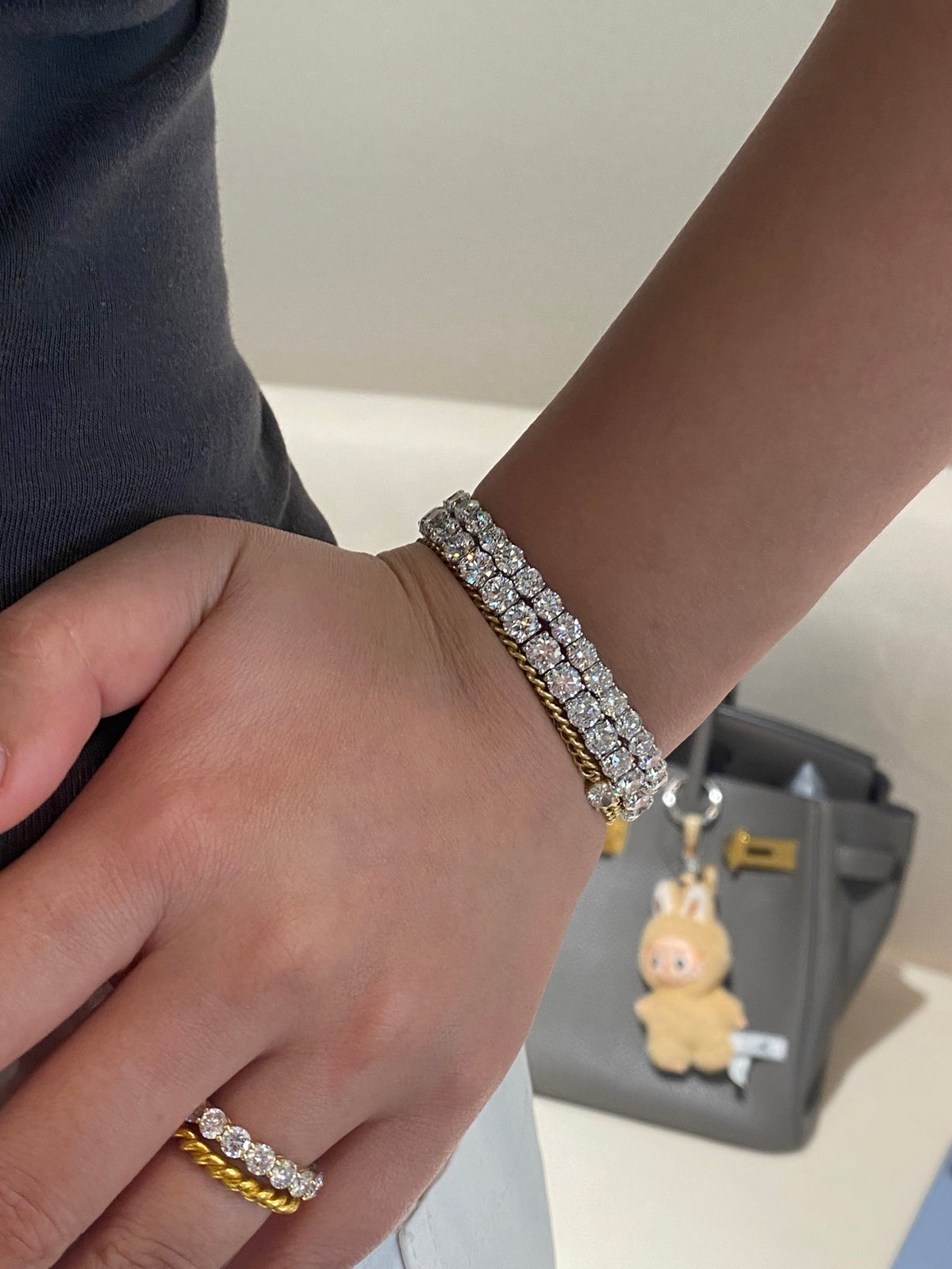 Larger white-metal tennis bracelet in layered wearing view; smaller bracelet, gold chain bracelet and ring not included