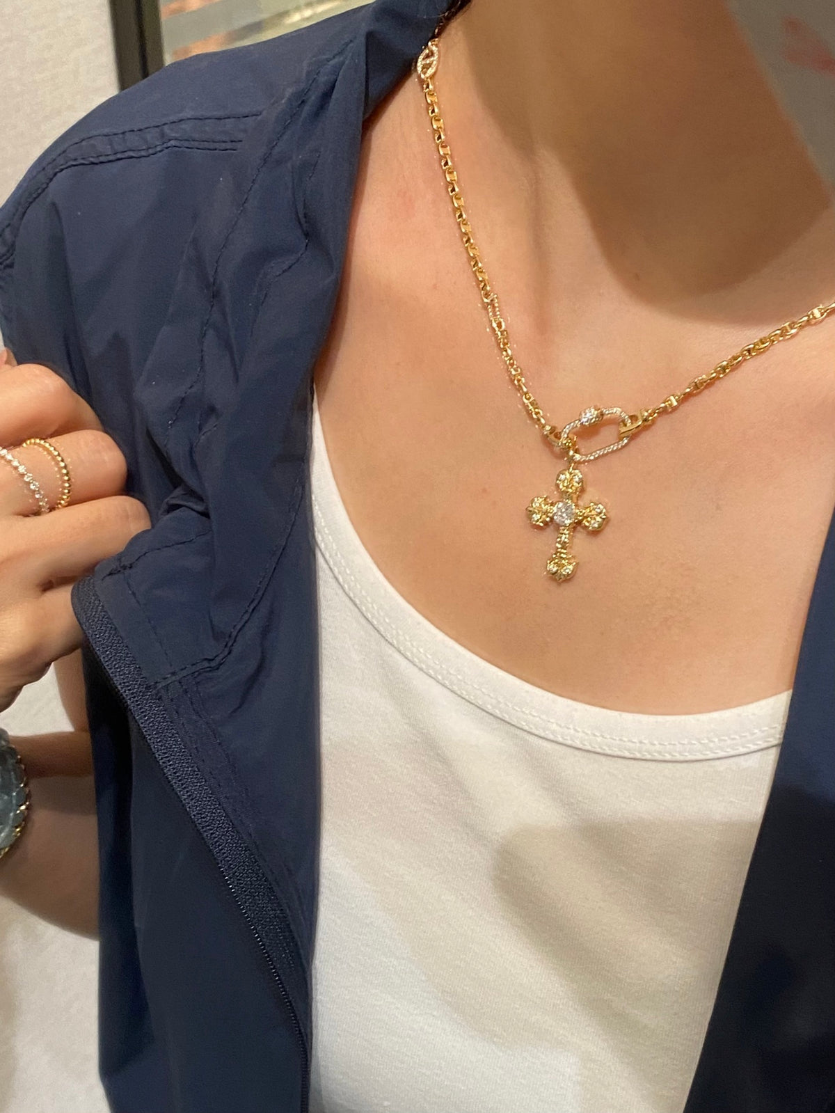 Flame cross lab-grown diamond pendant in yellow gold, original wearing view with blue jacket; chain and other jewelry not included