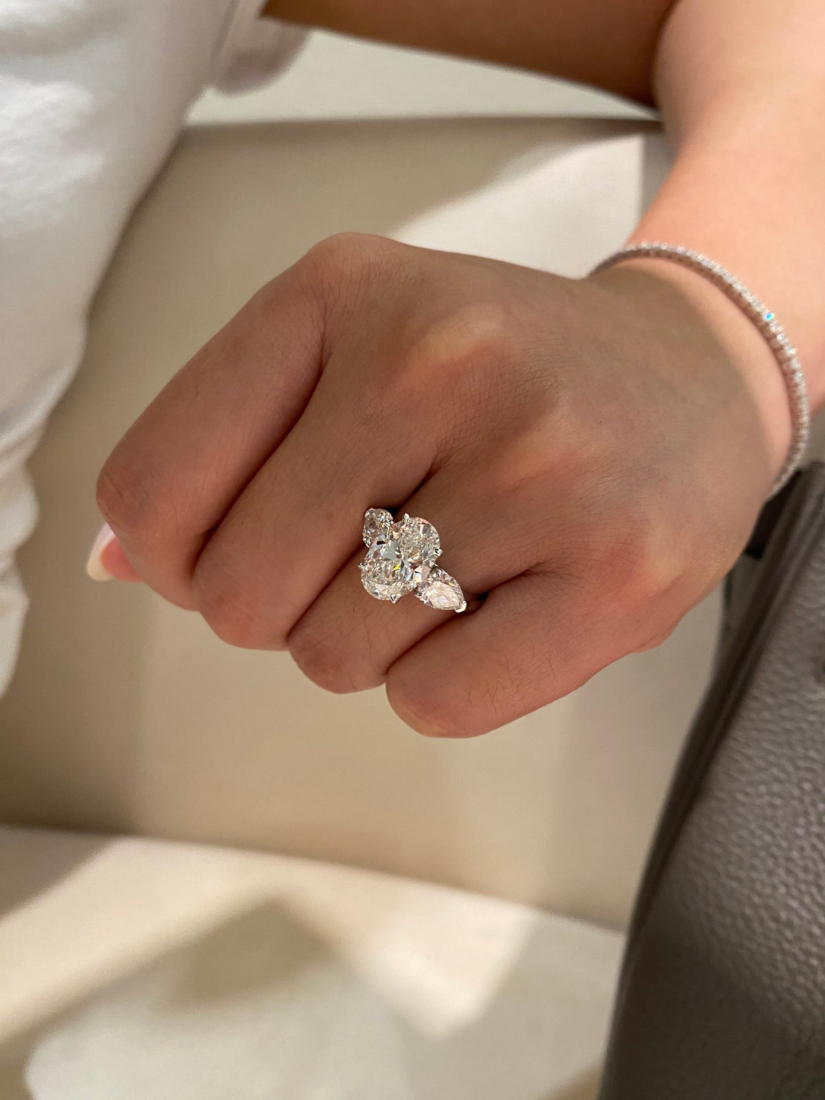 Oval and pear three-stone lab-grown diamond ring in white metal, original wearing view 1; other jewelry not included