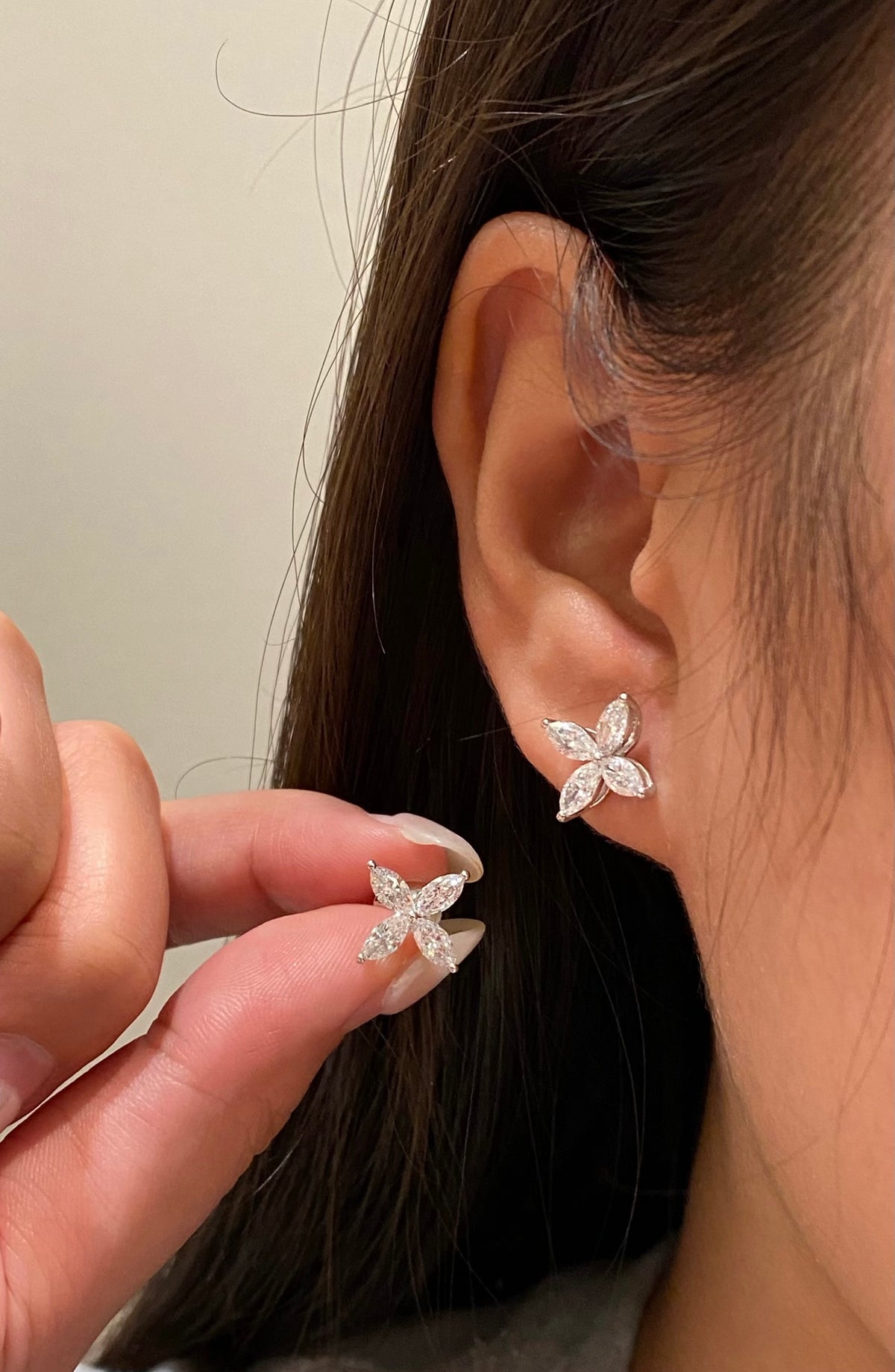 Four-petal marquise diamond stud earrings, original wearing and held-pair view 1