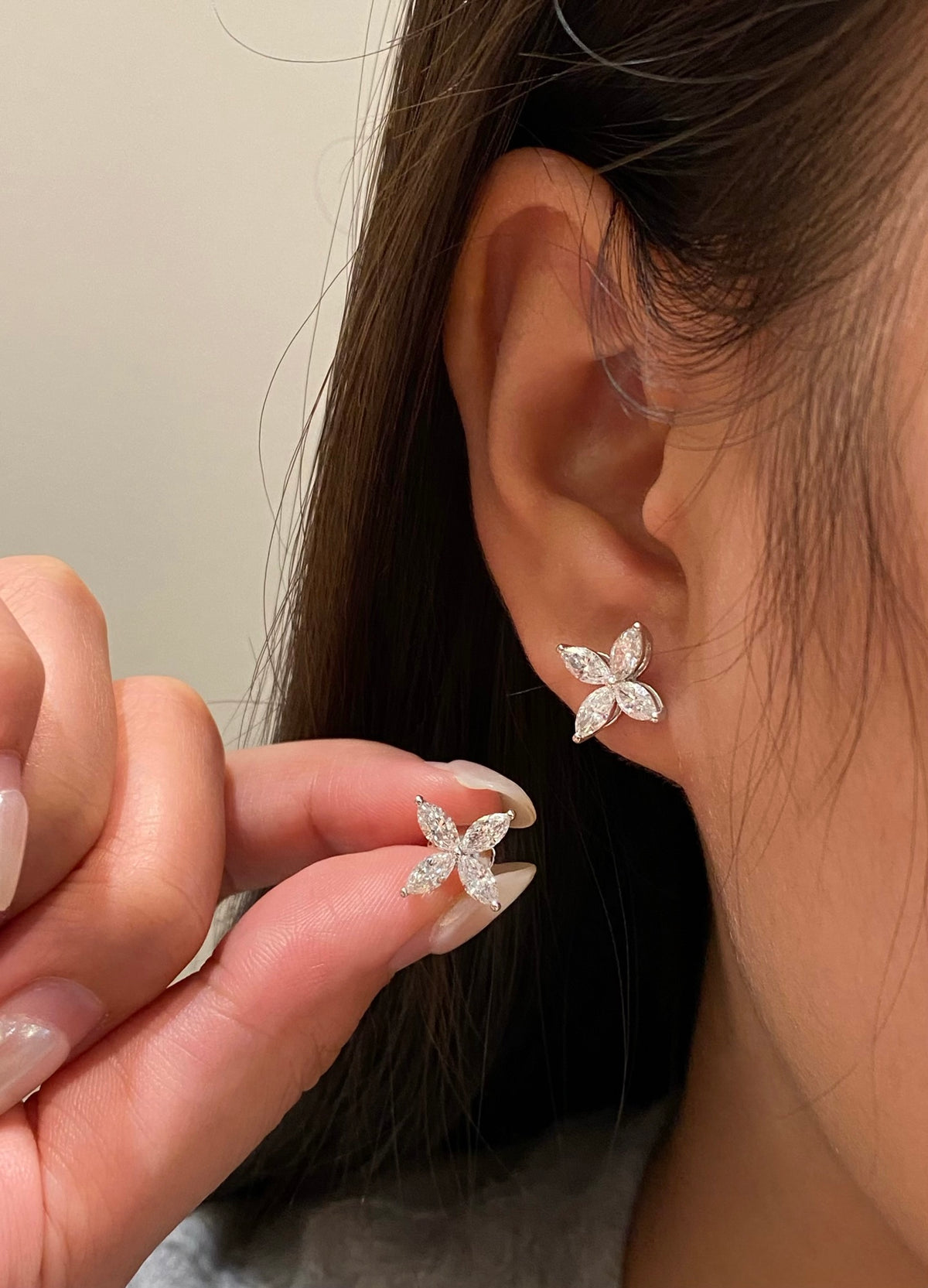 Four-petal marquise diamond stud earrings, original wearing and held-pair view 2