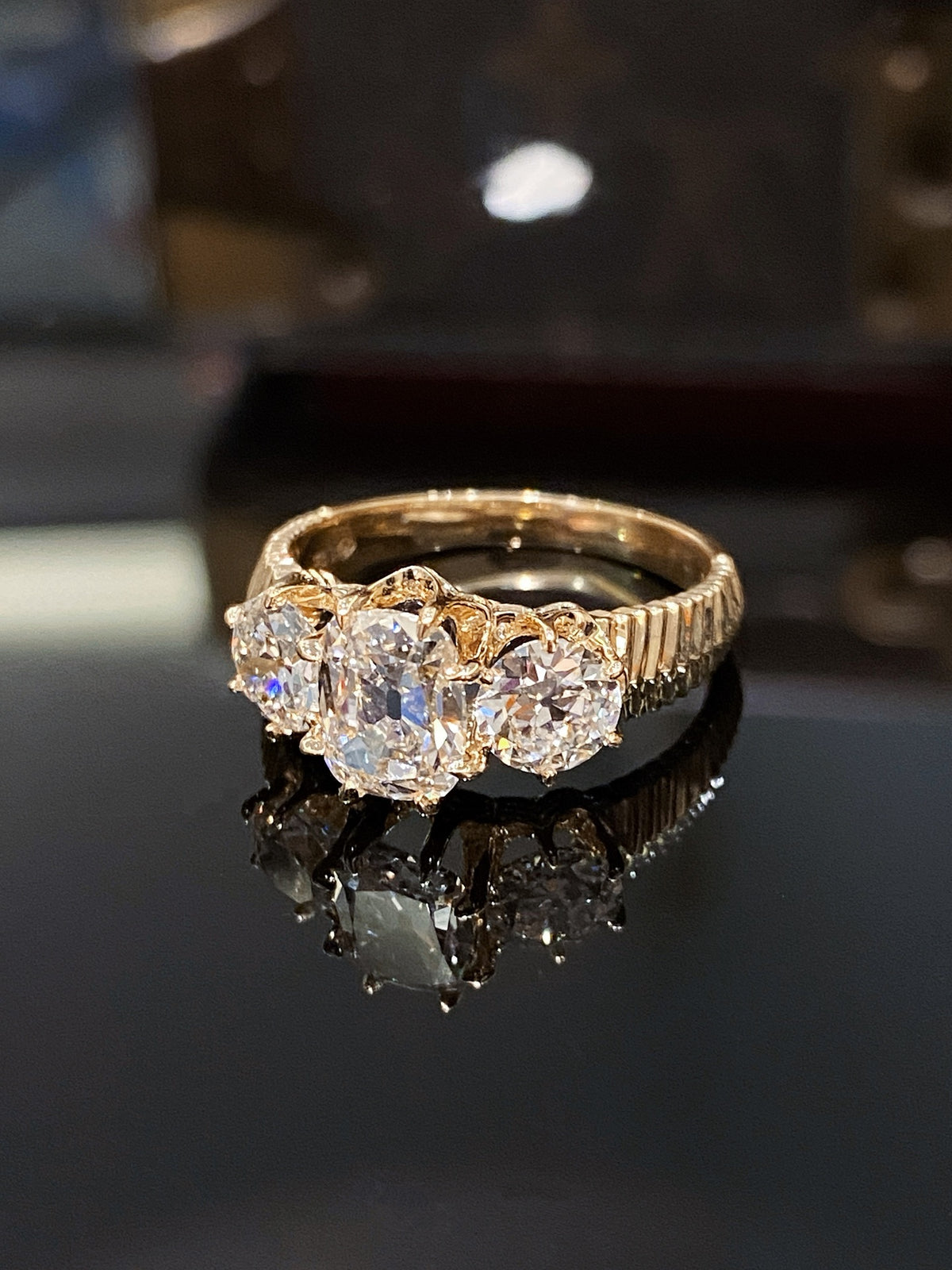 Old Mine-cut three-stone diamond ring in yellow gold, original angled view showing fluted shoulders