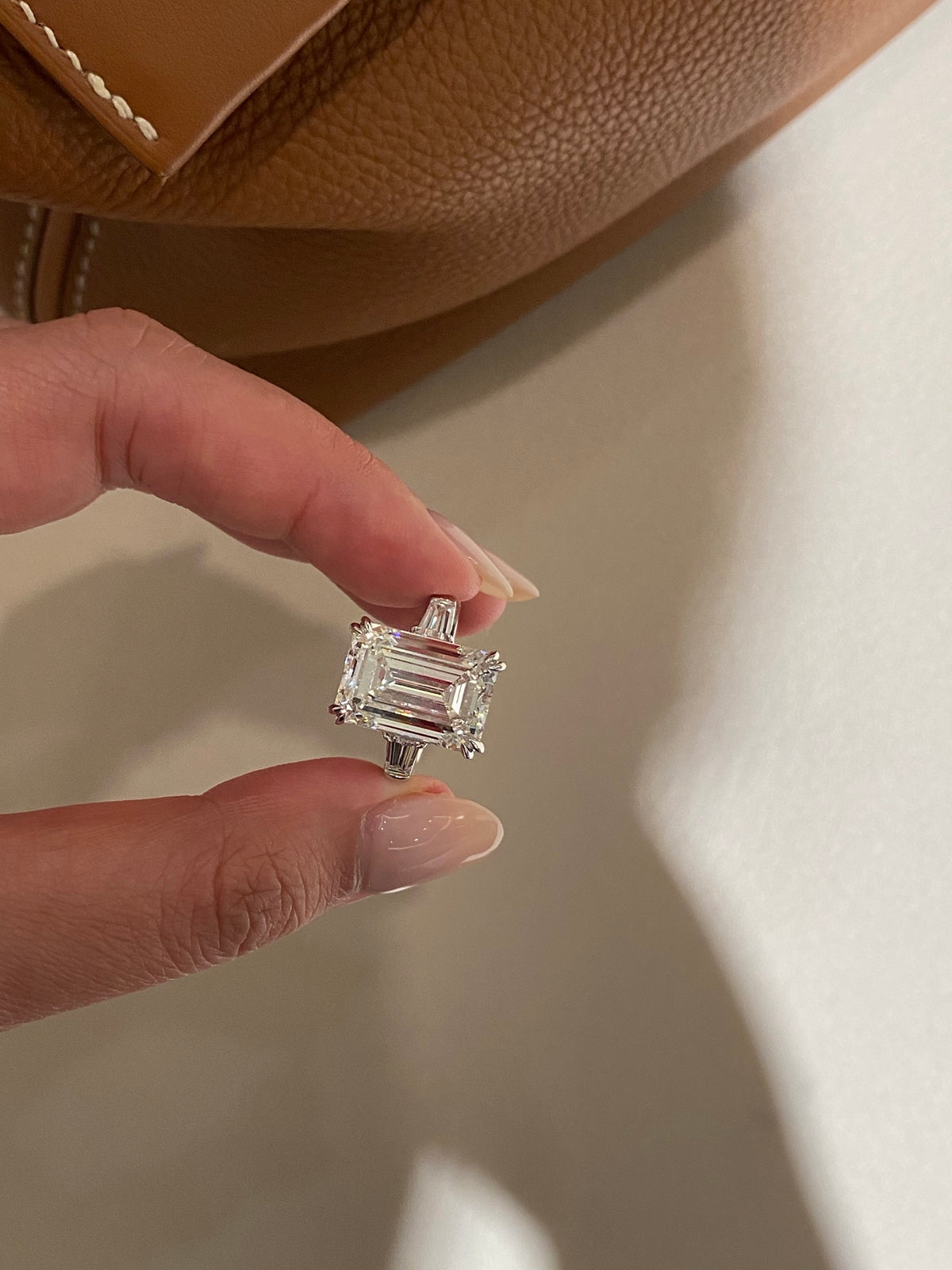 Emerald-cut three-stone diamond ring, original held face view