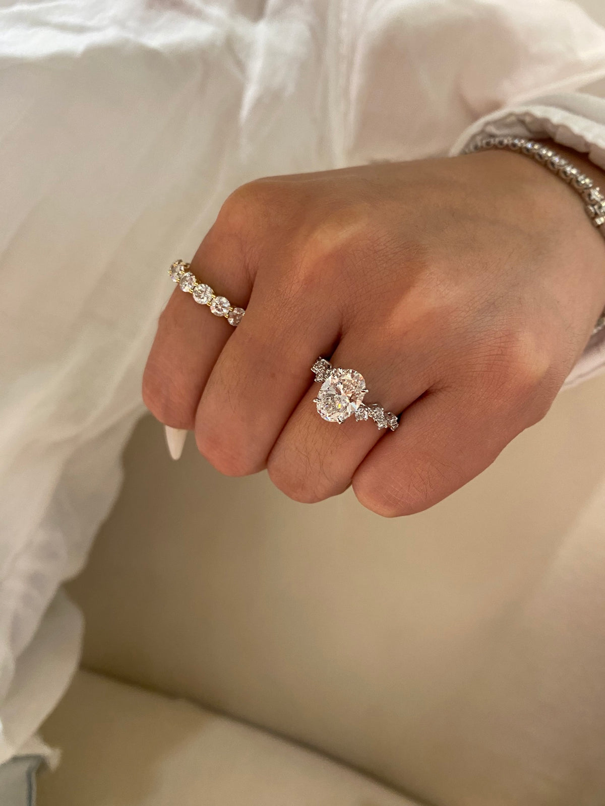 Oval diamond ring with geometric shoulders, original white-gold wearing view; other ring and bracelet not included