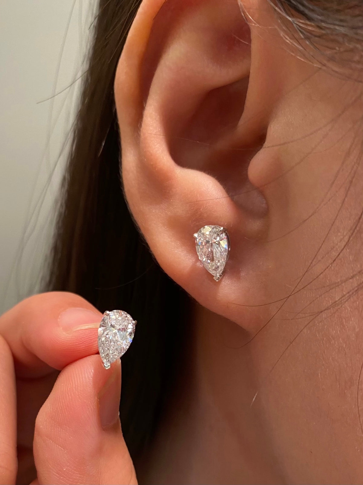 Pear-cut diamond stud earrings in white gold, original wearing view 2 showing reversed orientation