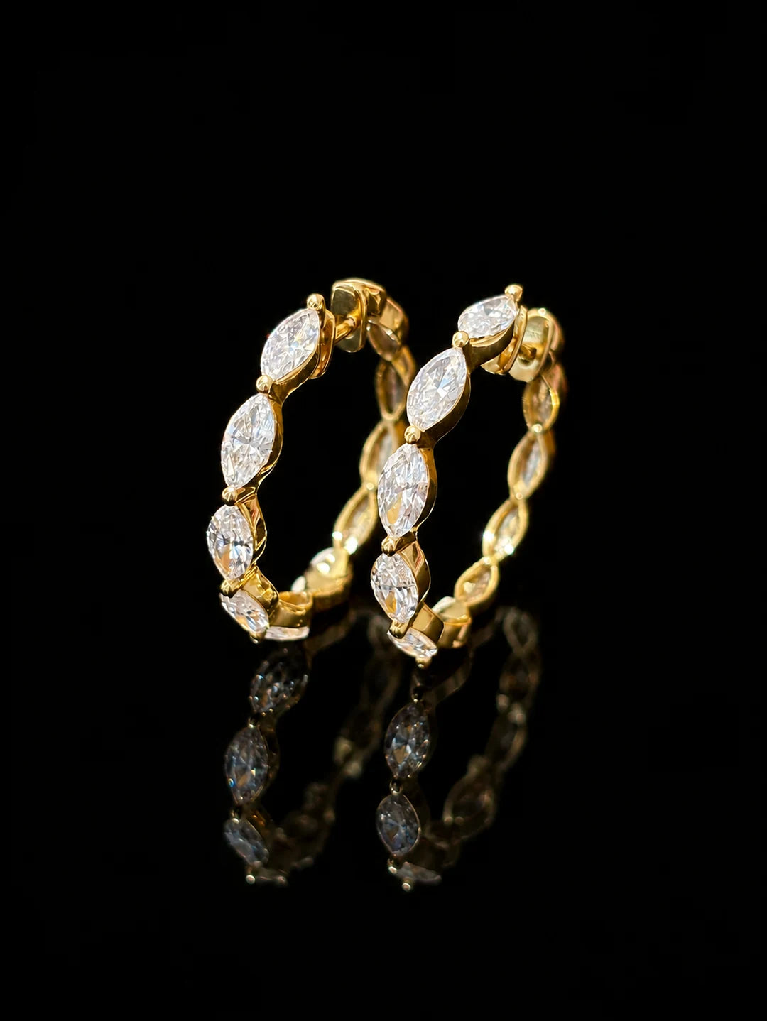 Marquise-stone gold hoop earrings on black mirrored glass