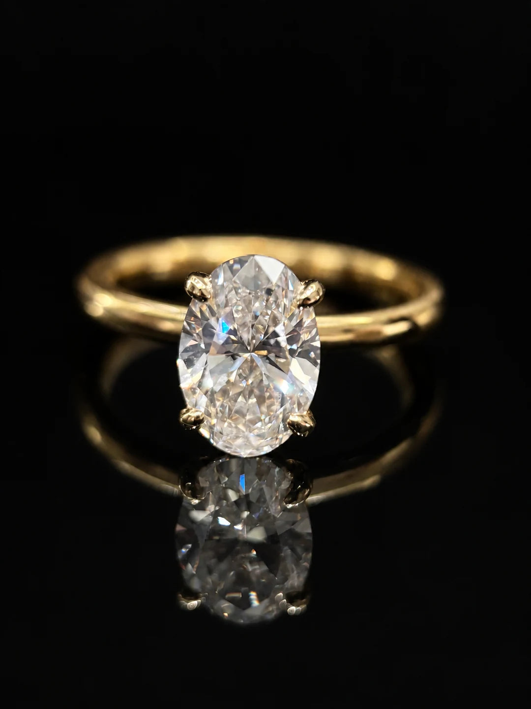Oval solitaire ring on black glass with its reflection