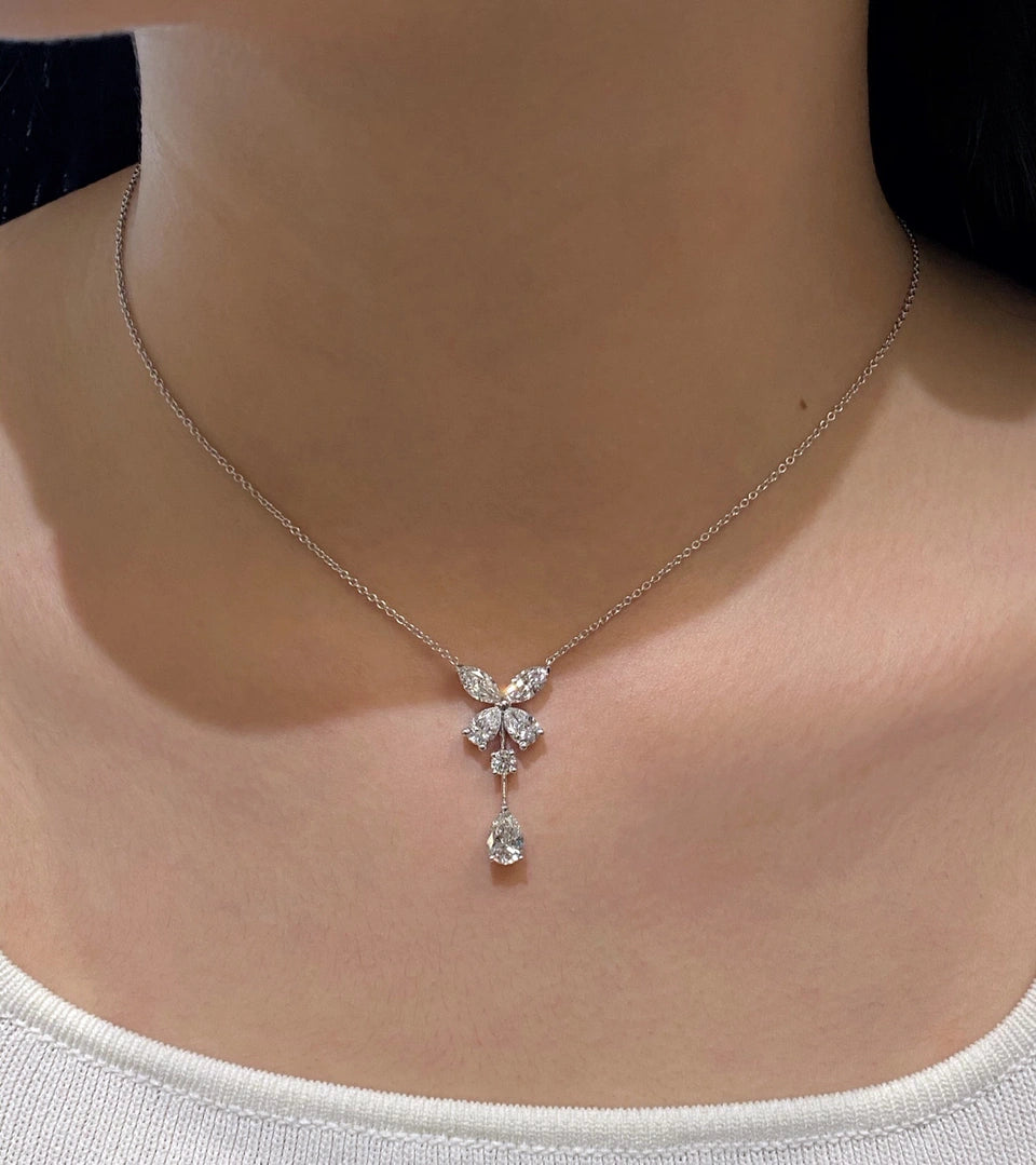 A butterfly-shaped pendant with a clear-stone drop, worn on a fine chain.