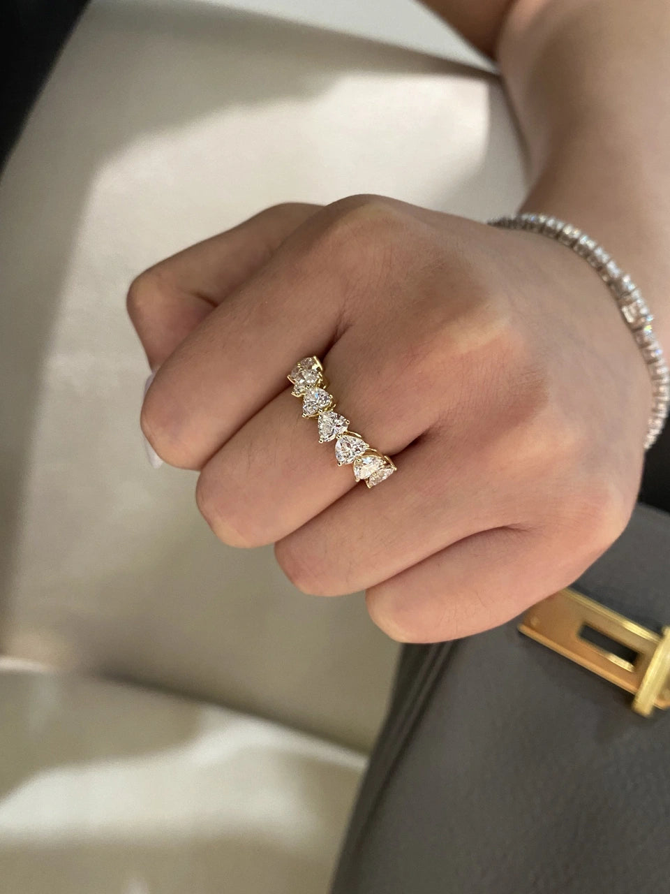 A clear-stone band with a yellow-tone setting worn on a hand.