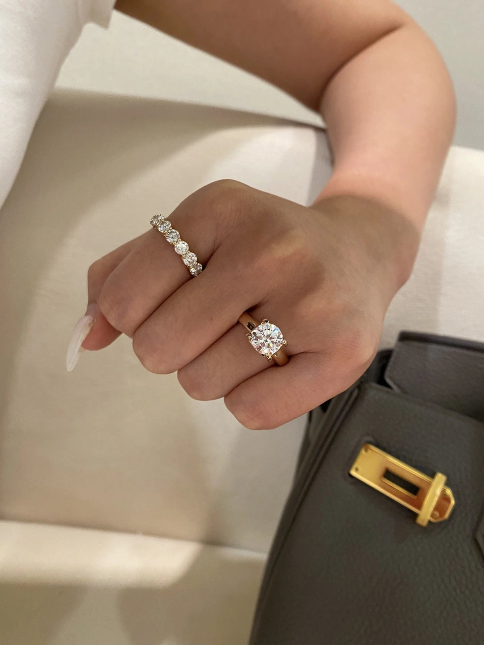 A clear-stone ring and a clear-stone band worn on one hand.